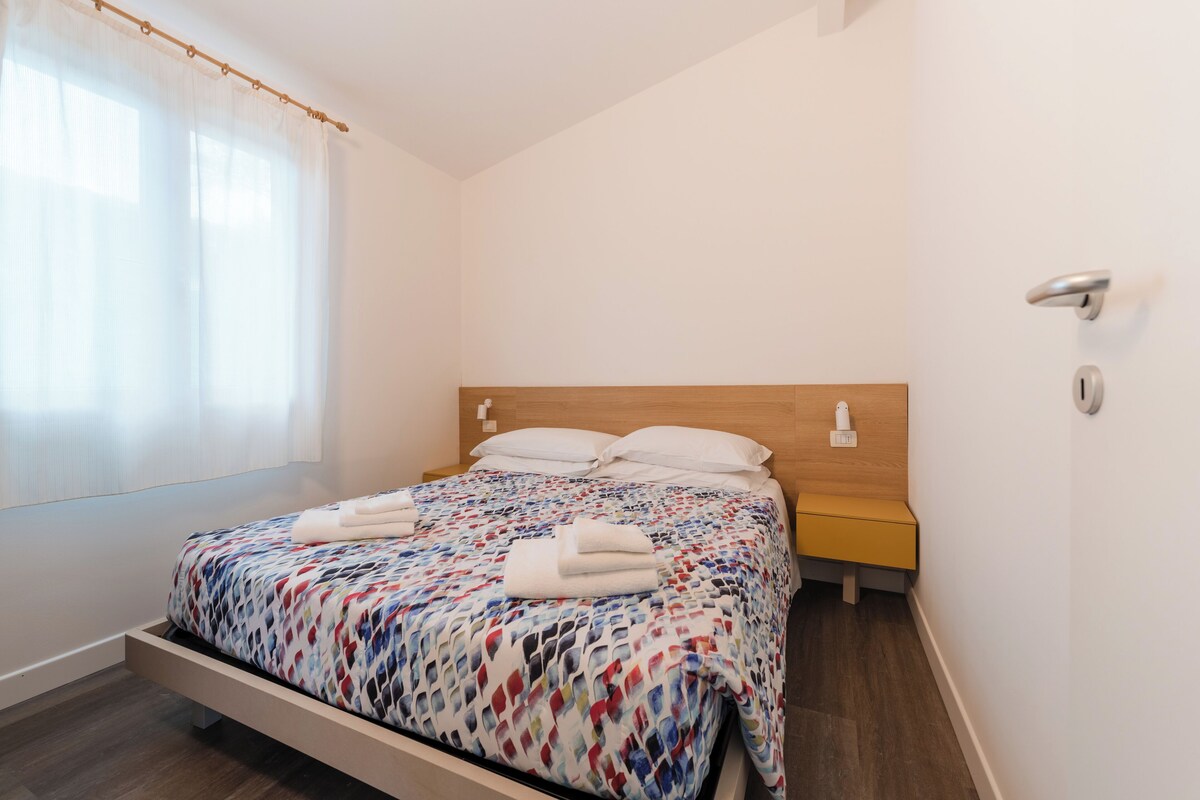 A neatly made bed with a patterned bedspread, a wooden headboard, and a bedside table with a lamp.