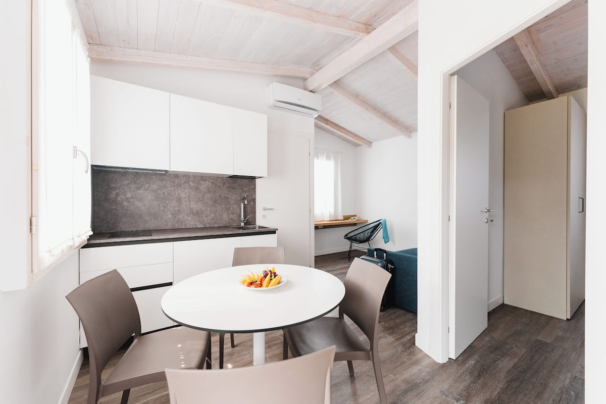 A modern kitchen with white cabinets, a round dining table with chairs, and a fruit bowl.