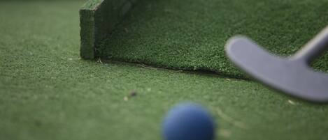 A close-up of a billiards cue and ball on a green felt surface.