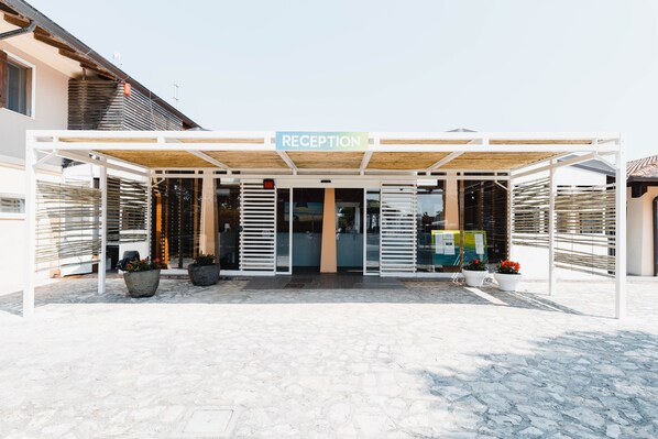 A reception area with a sign, potted plants, and a covered entrance. - Natural Village Resort (Potenza Picena)