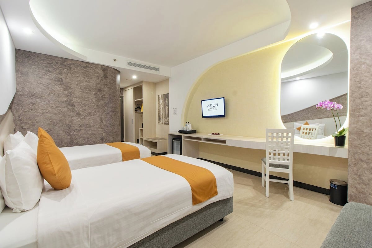 Una habitación de hotel moderna con dos camas, un escritorio y una zona de estar.