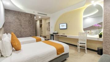 A modern hotel room with two beds, a desk, and a seating area.