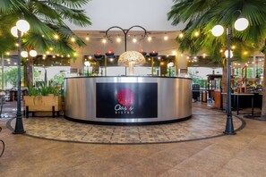 A bistro with a central counter, palm trees, and string lights. - Aston Cirebon Hotel & Convention Center (West Cirebon)
