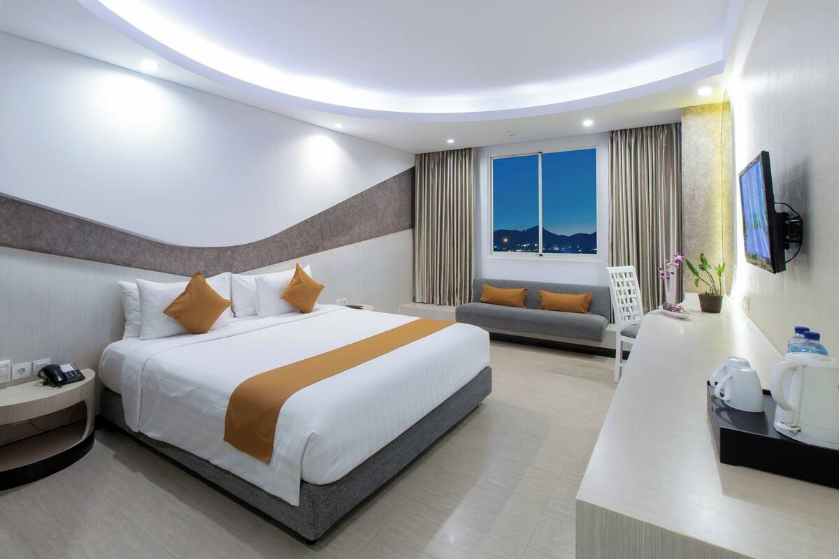Una habitación de hotel moderna con una cama grande, un sofá, un escritorio y una televisión.