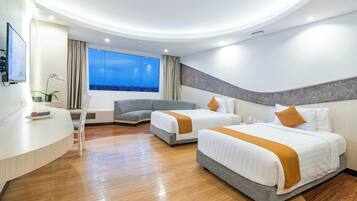 A modern hotel room with two beds, a curved desk, a TV, and a large window with a city view.