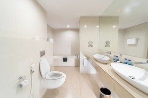 A modern bathroom with a toilet, bathtub, and two sinks. - Aston Cirebon Hotel & Convention Center (West Cirebon)