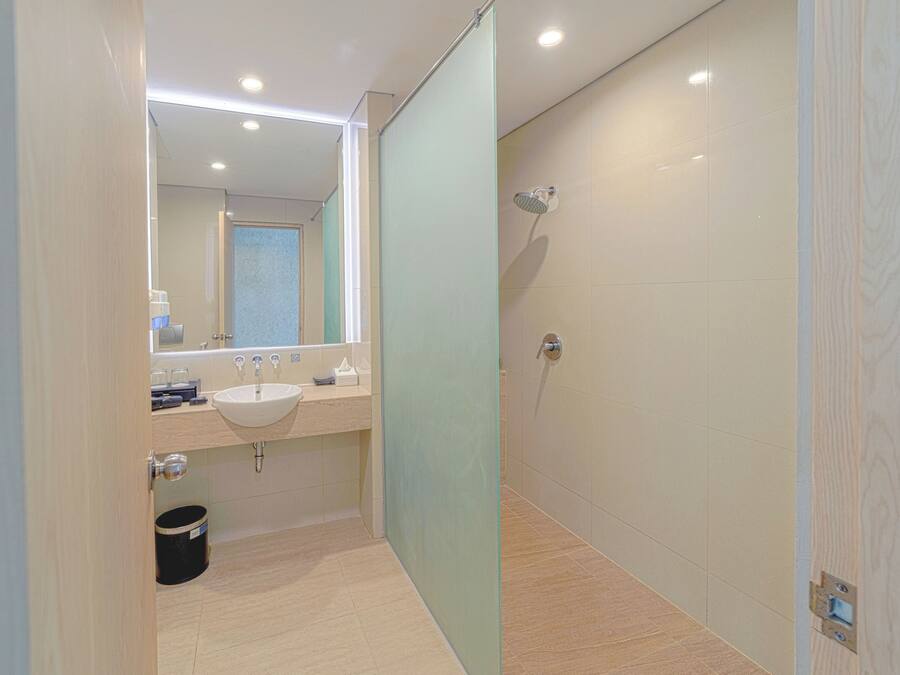 A modern bathroom with a glass partition, a sink, and a shower.