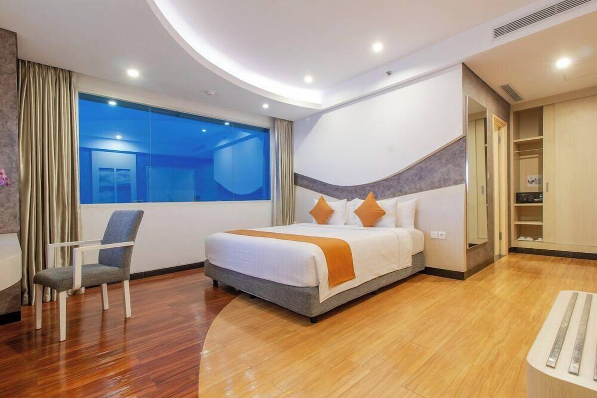 Una habitación de hotel moderna con una cama grande, una silla, un armario y vistas a la ciudad.