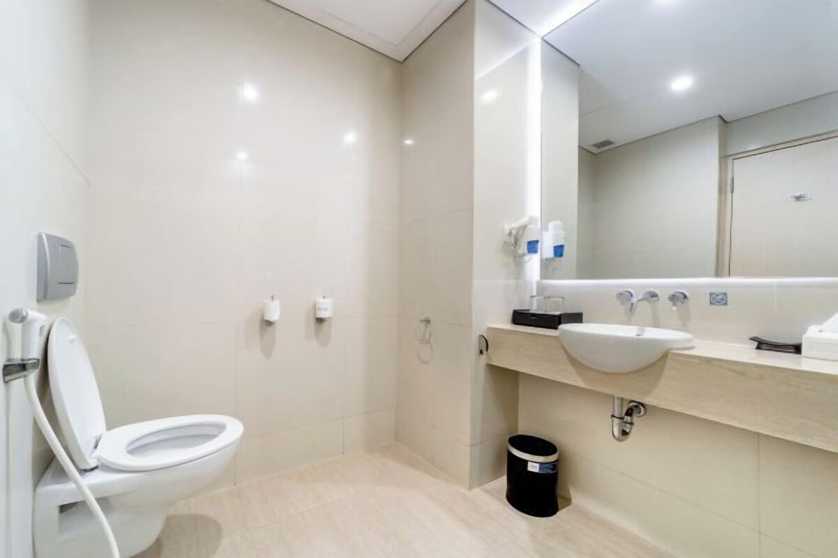 A modern bathroom with a toilet, sink, and mirror.