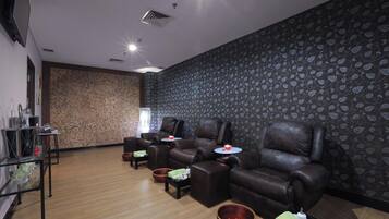 Una habitación con varios sillones de cuero, una mesita pequeña y una pared con un diseño de hojas.