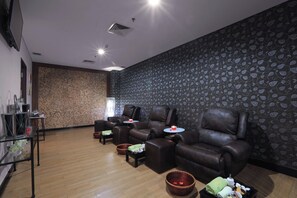 A room with multiple leather recliners, a small table, and a wall with a leaf pattern. - Aston Cirebon Hotel & Convention Center (West Cirebon)