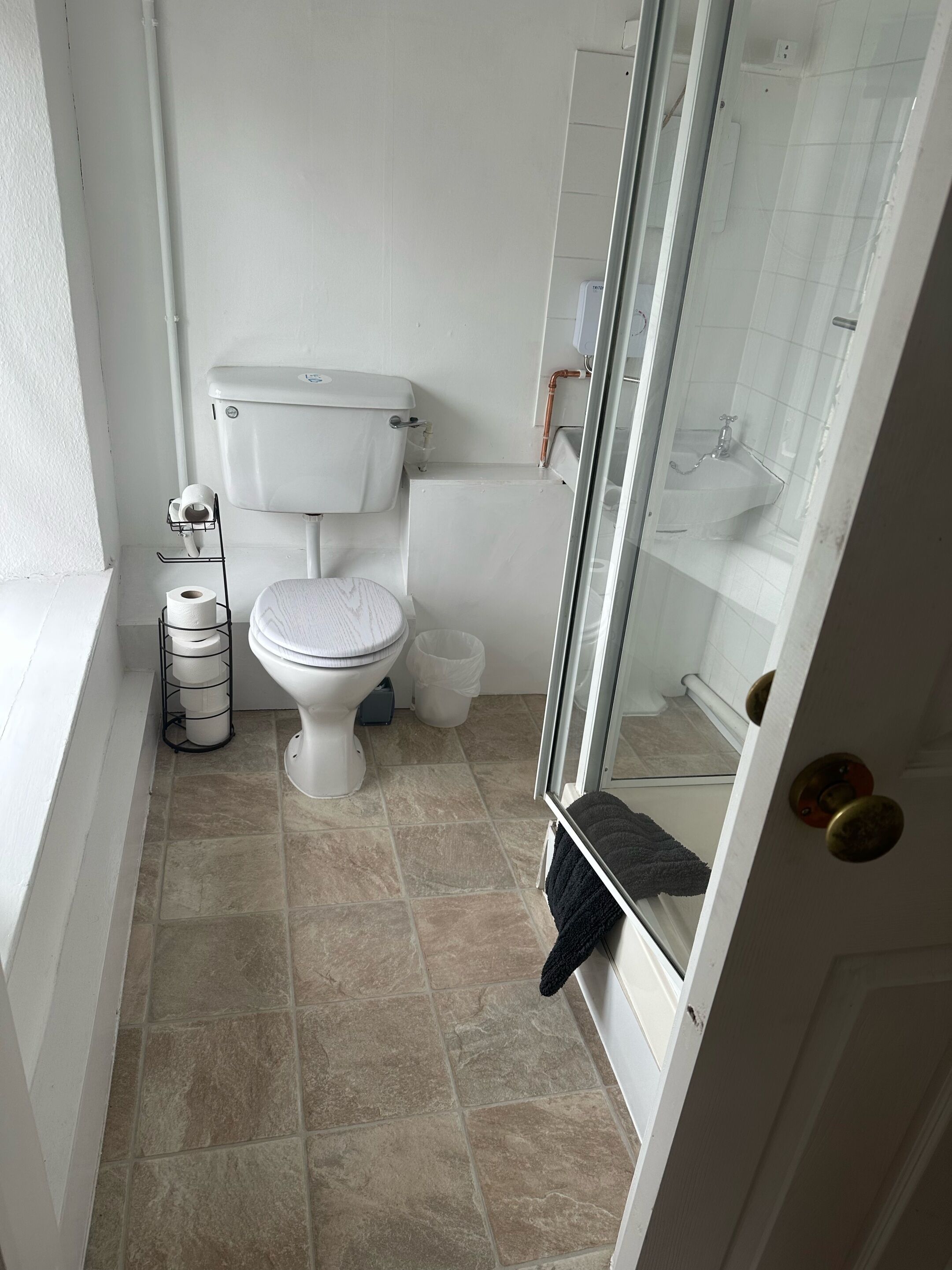 A small, clean bathroom with a toilet, sink, and shower.