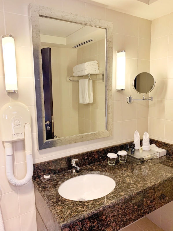 A bathroom with a large mirror, a sink, a towel rack, and a hand dryer.