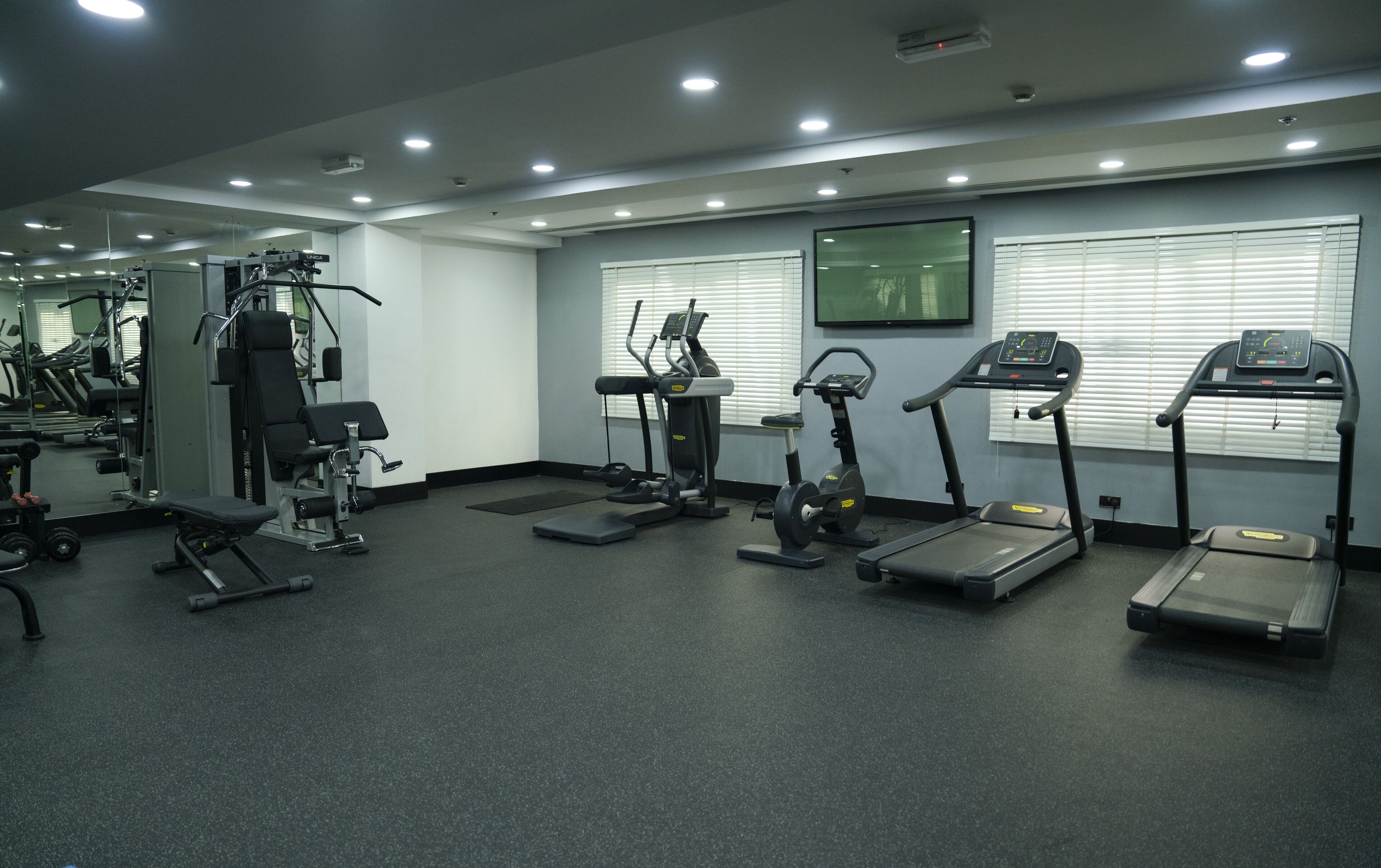 Un gimnasio con diferentes equipos de ejercicio, incluyendo cintas de correr, elípticas y máquinas de pesas.