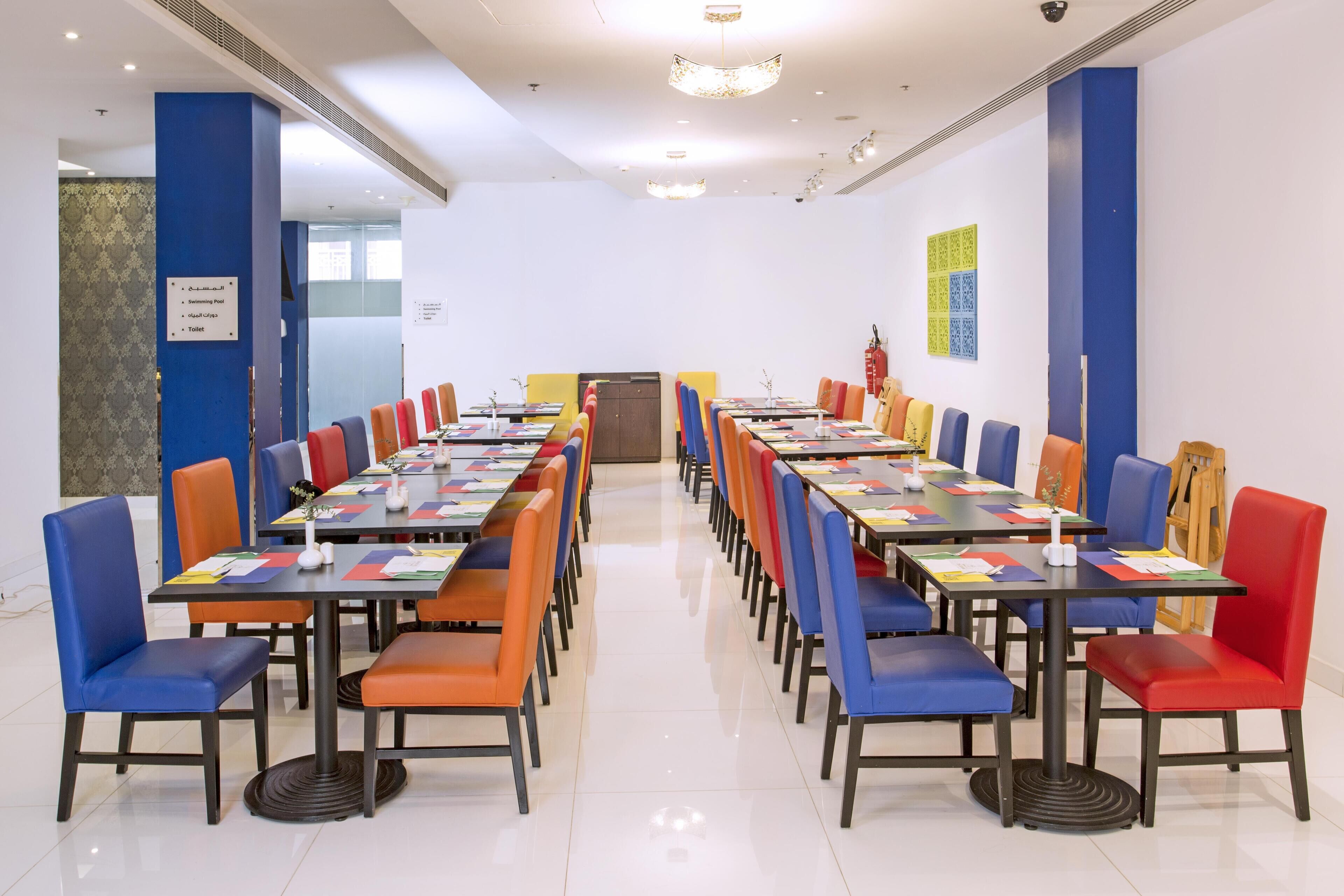 Une salle de conférence équipée de plusieurs tables et chaises, d’un pupitre et d’un panneau indiquant l’emplacement des toilettes.