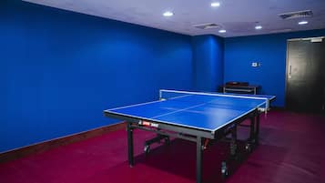 Una habitación con mesa de ping pong, paredes azules y alfombra roja.