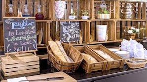 Mostrador de panadería con panes, pasteles y un cartel de pizarra.
