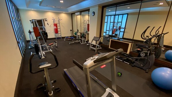 A gym with various exercise equipment, including treadmills, stationary bikes, and free weights. - Samal Resort & Spa (Almaty)