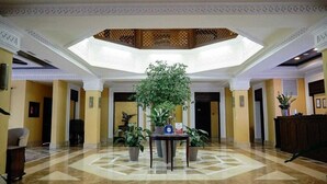 A spacious lobby with a high ceiling, a central plant, and a checkered floor. - Samal Resort & Spa (Almaty)