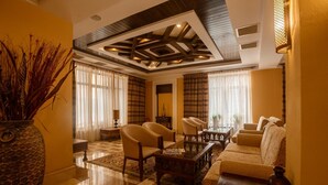 A spacious living room with a checkered floor, a large stone vase, and a ceiling with exposed beams and recessed lighting. - Samal Resort & Spa (Almaty)