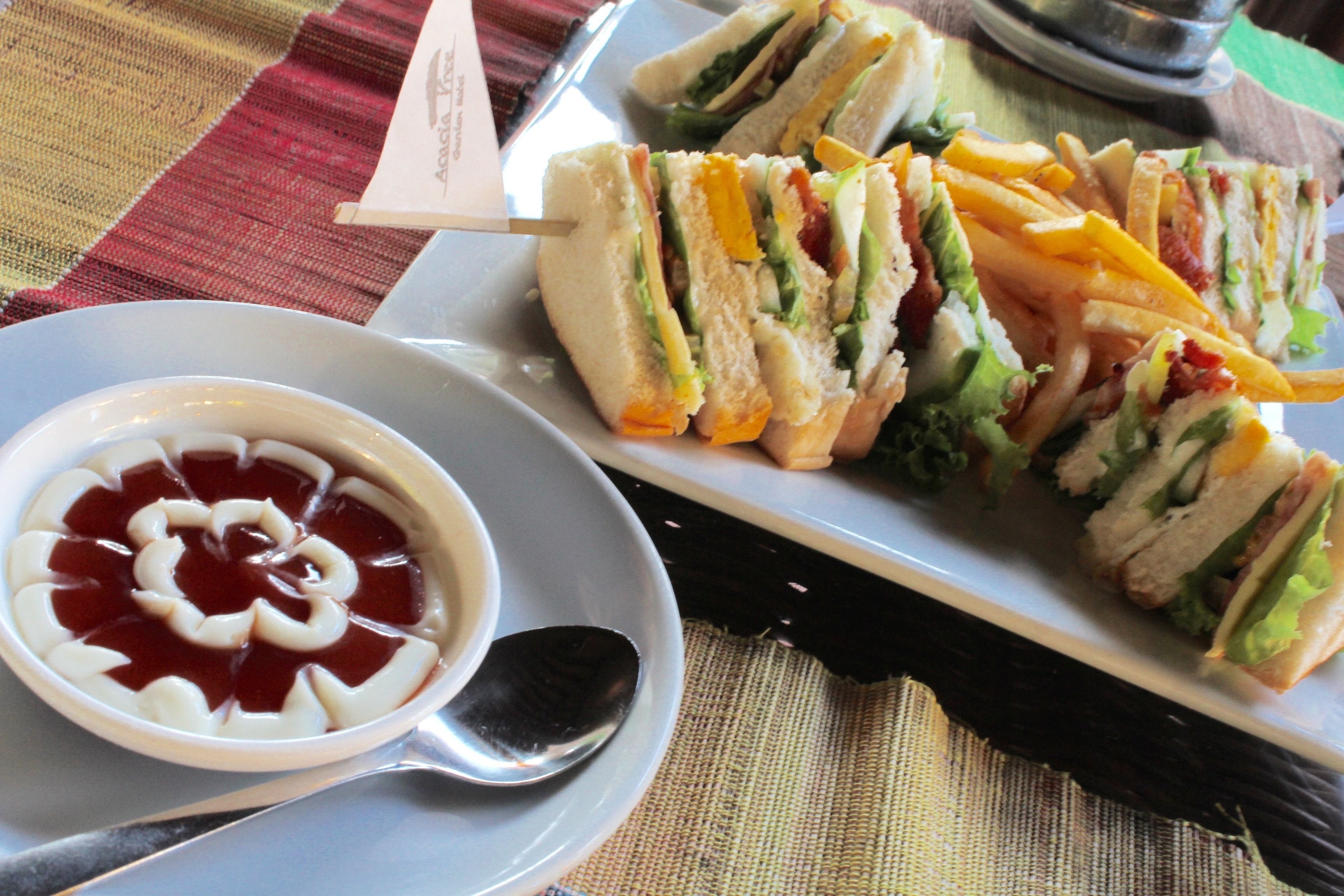A plate of sandwiches and a bowl of jelly dessert.
