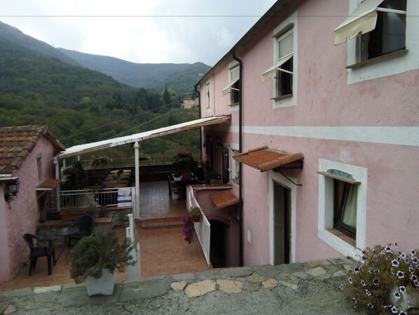 Un bâtiment rose doté d’un balcon, d’une terrasse et offrant une vue sur des collines verdoyantes.