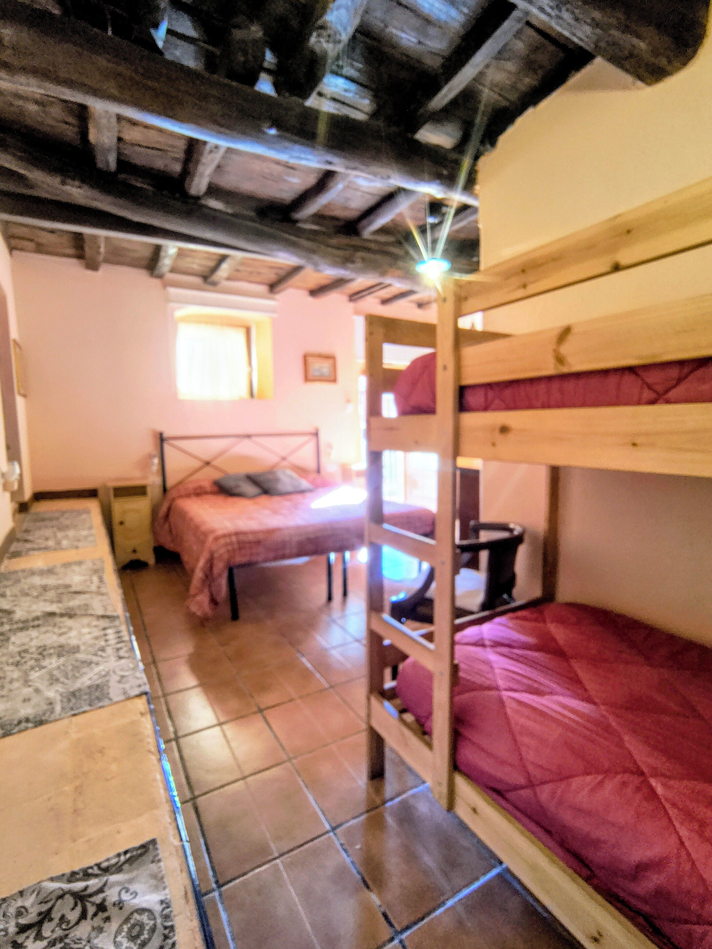 Una camera del dormitorio con letti a castello, una piccola finestra e pavimento piastrellato.