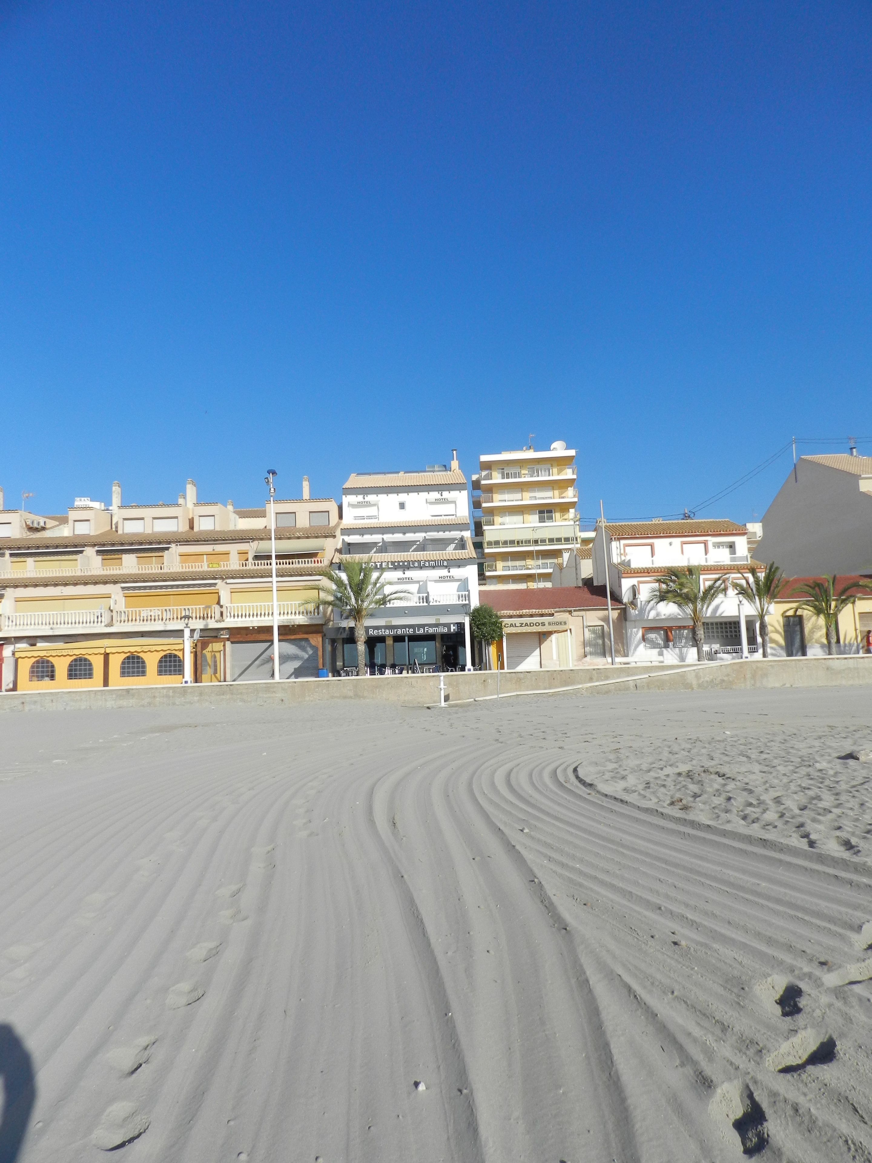 A beachfront hotel with multiple stories, a restaurant named 'Restaurante La Familia', and a visible sandy beach.