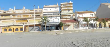 A beachfront hotel with multiple stories, a restaurant named 'Restaurante La Familia', and a visible sandy beach.