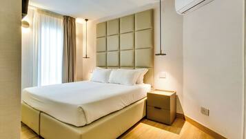 Ein modernes Hotelzimmer mit einem großen Bett, Nachttischen, einer Klimaanlage und einem Fenster mit Vorhängen.