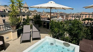 A rooftop pool area with lounge chairs and an umbrella, overlooking a cityscape with historic buildings. - Relais Badoer (Rome)