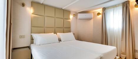 A modern hotel room with a large bed, a headboard with illuminated panels, a bedside table, and an air conditioning unit.
