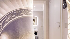 A spiral staircase with ornate designs, leading to a room with a wooden floor and a white door. - Relais Badoer (Rome)