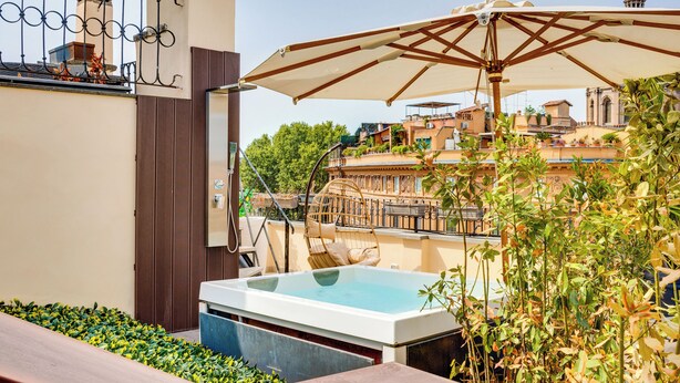 A rooftop pool area with a hot tub, a swing chair, and an umbrella. - Relais Badoer (Rome)