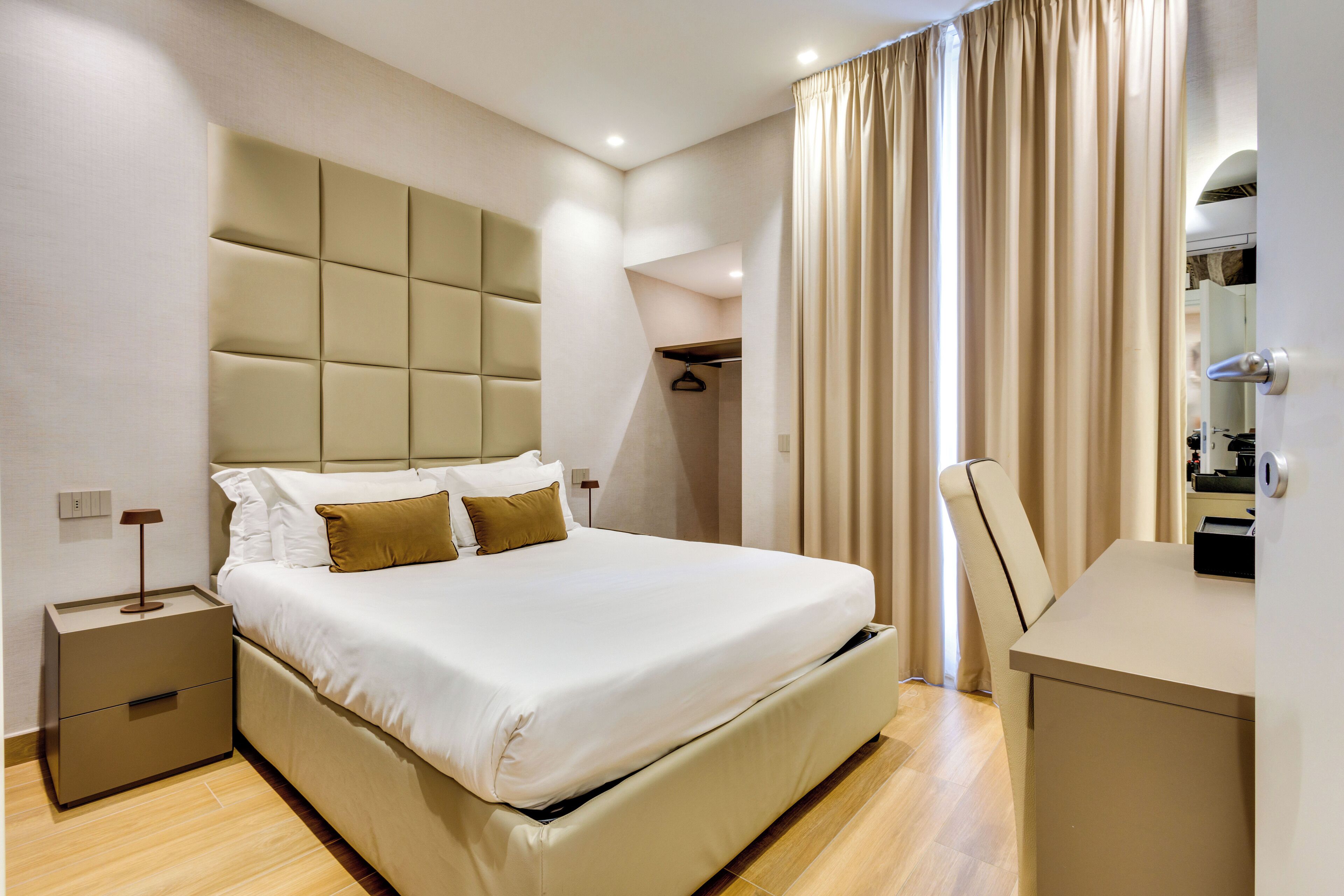 Una habitación de hotel moderna con una cama grande, una mesita de noche, un escritorio y un armario.