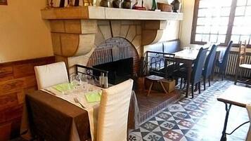 Een eetruimte met een open haard, een tafel met stoelen en een vloer met patroon.