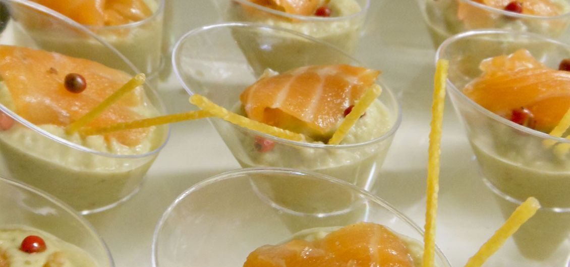 Varios vasos transparentes con un postre verde, rodajas de naranja y adornos.