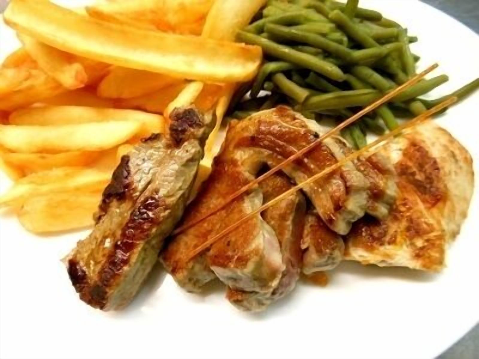 A plate with grilled chicken, French fries, and green beans.
