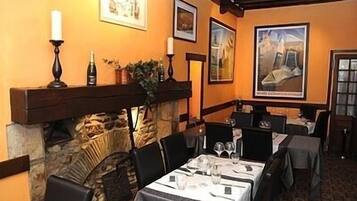 Un restaurante con paredes de piedra, cuadros enmarcados y mesas preparadas para comer.