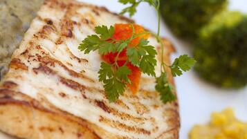 A grilled chicken breast with a garnish of parsley and a side of broccoli.