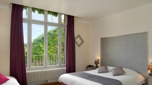 A hotel room with a bed, a window with curtains, a radiator, and a bedside table with a lamp. - Hôtel de l'Ecu de France (Le Malesherbois)