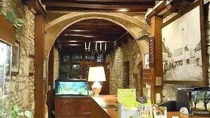 A reception area with a wooden desk, a fish tank, and a painting on the wall. - Hôtel de l'Ecu de France (Le Malesherbois)