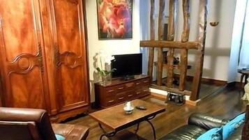 Ein Wohnzimmer mit einem Holzschrank, einem Fernseher auf einem Holztisch, einer Couch und einem Couchtisch.