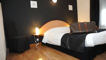 Una habitación de hotel con una cama, una silla, una mesita de noche y una lámpara.