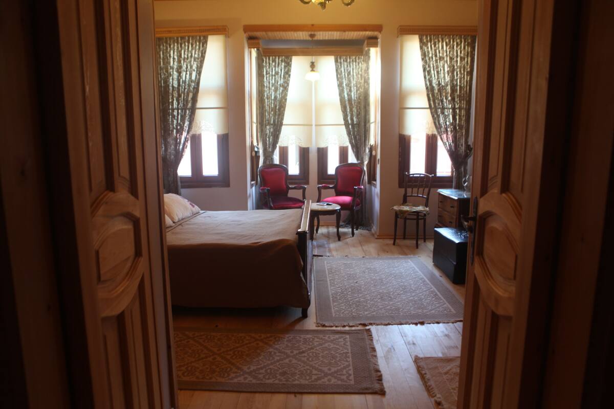 Une chambre à coucher avec un lit, deux chaises, une petite table et une commode.