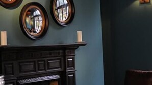 Ein Zimmer mit dunklem Holzofen, blauer Wand und Ledersessel.