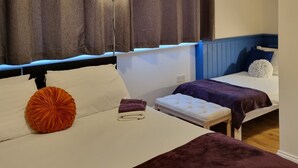 Ein Hotelzimmer mit zwei Betten, einem Nachttisch, einer Lampe und einem großen Fenster mit Vorhängen.