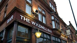 Ein Gebäude mit einem Schild, auf dem „THE WINDMILL BAR“ steht, und einem Schild „ESSZIMMER“ über dem Eingang.