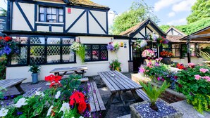 A traditional building with a white facade and dark trim, featuring outdoor seating and hanging flower baskets. - Ye Olde Red Lion (Newbury)