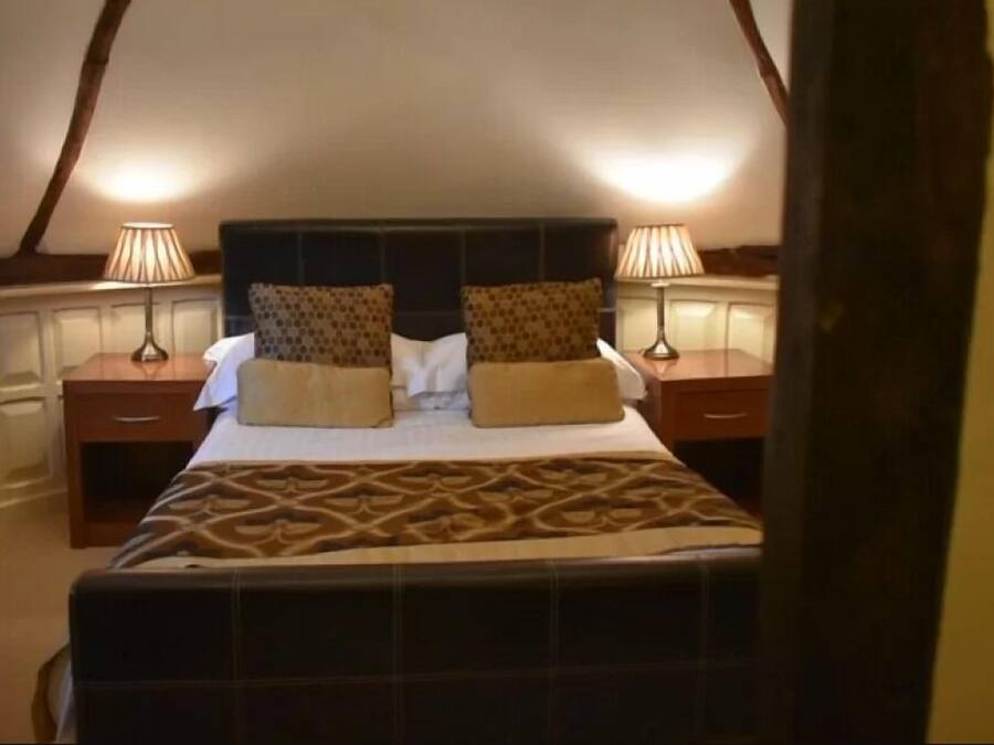 A bedroom with a large bed, two bedside tables, and two lamps.